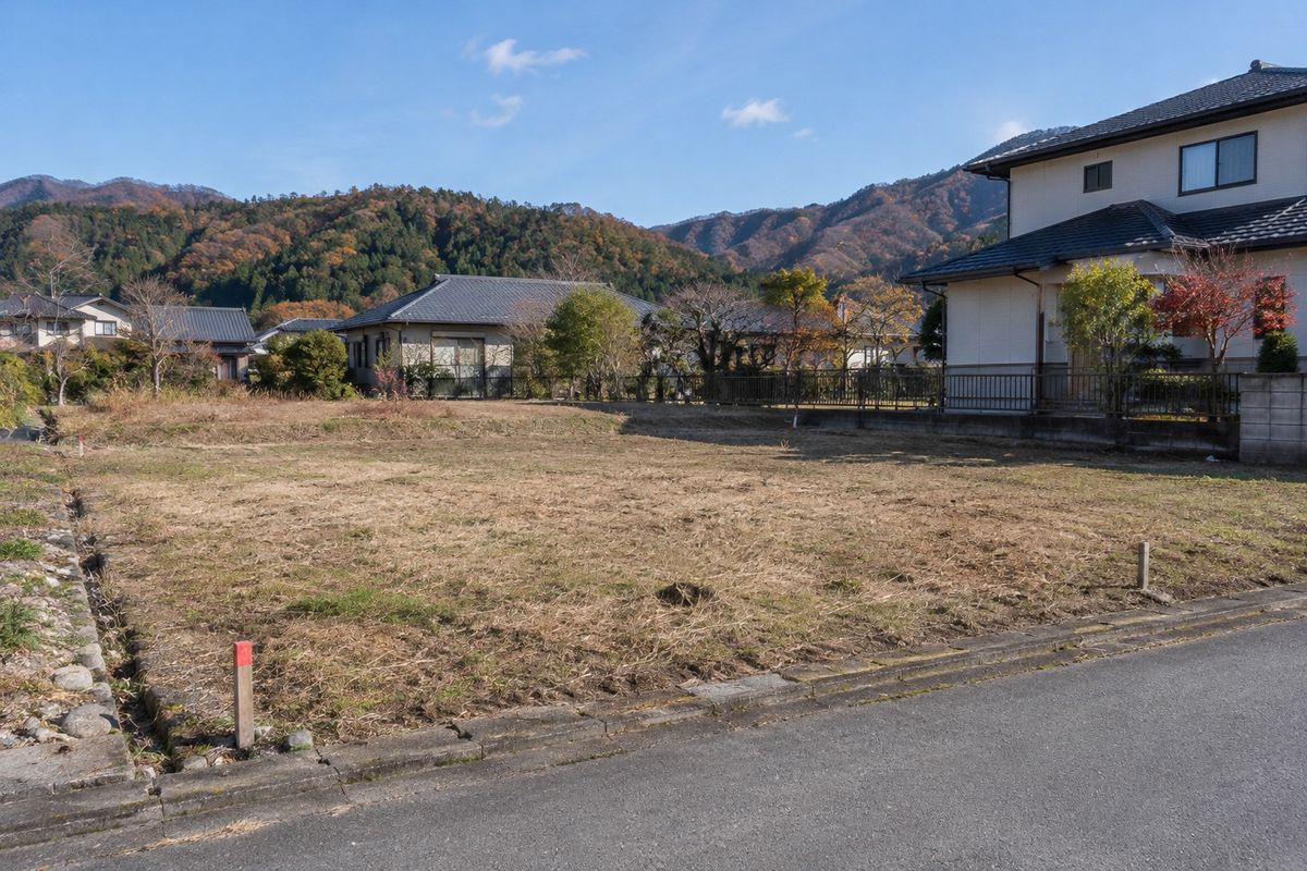 長野県郊外の売り土地の空き地と、隣の住宅・里山